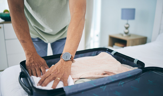 Man packing a suitcase at home for travel. 