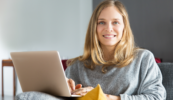Woman smiling and sitting with laptop at home.
