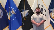 Nathaniel Toups standing in form of various flags.