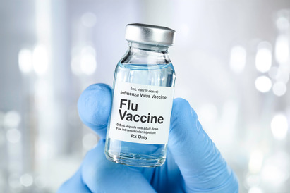 Gloved hand holding a flu vaccine vial. 
