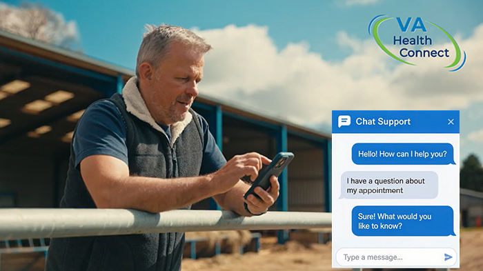A man sends a text message while leaning over a fence on a farm.