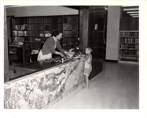 librarian helping small child at desk in black and white