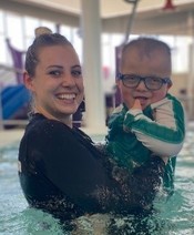 A staff supporting a young participant in the pool