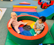 2 toddlers sitting in soft play equipment