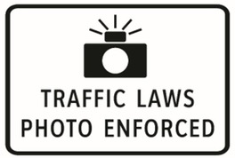 speed camera warning sign that reads "Traffic laws photo enforced"