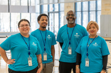 Four Staffpersons of different ages smiling looking at campera in gymnasium