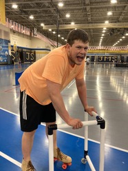 A boy smiling while skating and being supported by a skate walker.