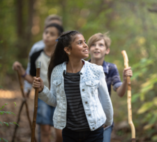 a young teen girl is hiking through the woods with a group of others, appears amazed by her surroundings.