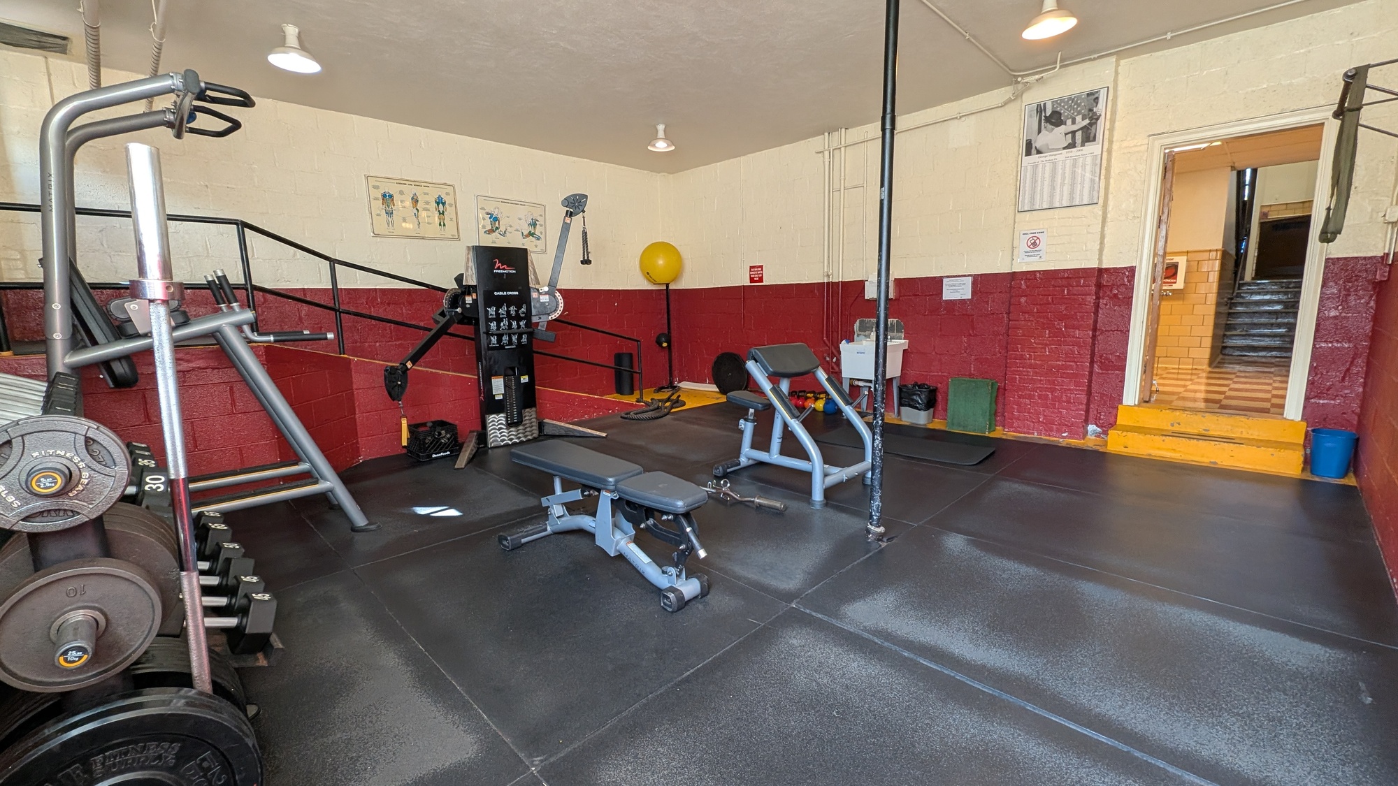 A fitness center with various equipment and red walls.