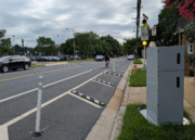 ID: a speed camera faces away from the camera towards a flashing school zone speed limit beacon on an arlington street.