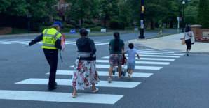 ID: a crossing guard helps people cross the street in front of a school 