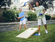 Two women outdoors playing cornhole.