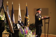 Chief Penn standing at the podium giving his remarks during Corporal Barry Foust's funeral service