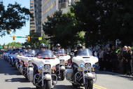 ACPD Motor Officers riding two by to down a street while officers salute
