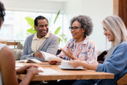 A group of people sitting around a table discussing books.