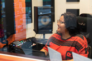 A teenage girl using studio equipment in a sound booth