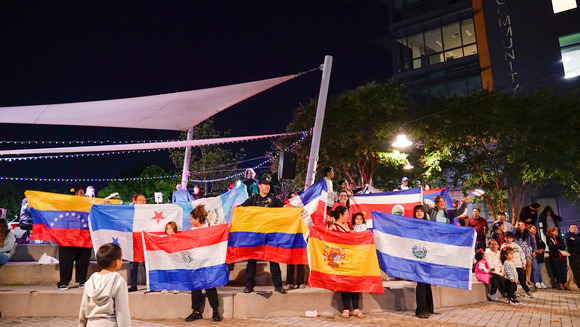 A group of people holding up flags for various Latin American nations.