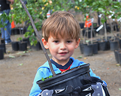 A young child holding a potted young tree
