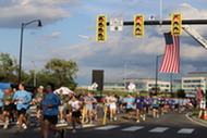 Runners run under the flag at the Arlington 9/11 5k.