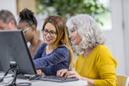 A woman helping a senior use a computer.