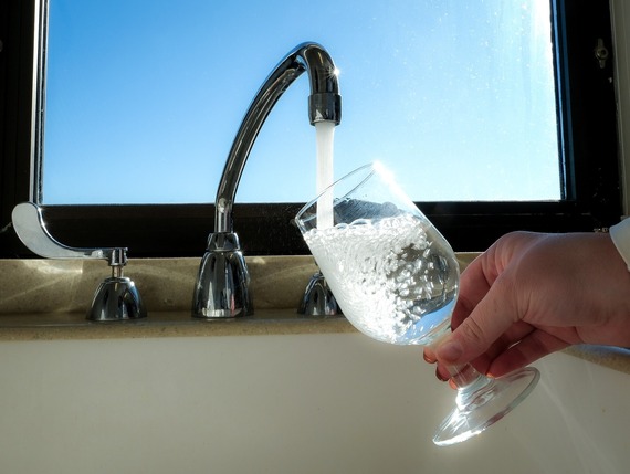 An image of water flowing from a faucet and filling a glass