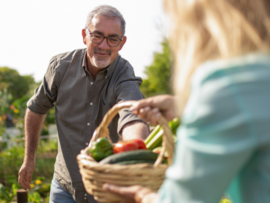 Man passing a basket of vegetable from the garden to a women