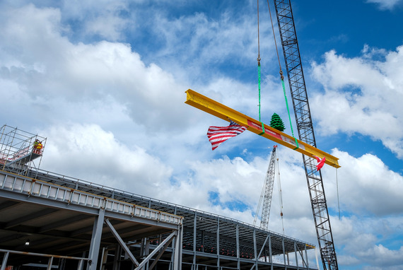 A steel beam is hoisted into the sky by crane at LEGO's Oct. 30 topping-out ceremony