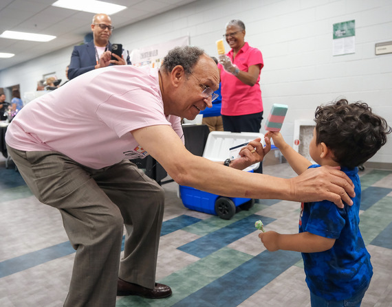 Dale District Supervisor Jim Holland hands a popsicle to a young boy at Chesterfield's 2024 Cafe con la Comunidad event
