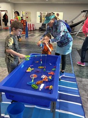 Children and adult playing an inside fishing game carnival