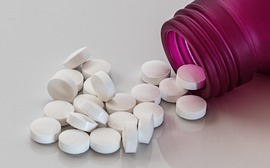 A bottle of prescription medication with pills spilling out
