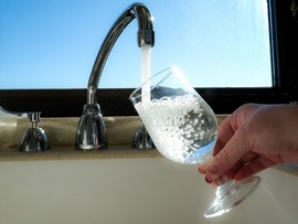 Tap water flows out of a faucet into a glass 