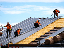 Construction workers install a metal roof on an industrial building in Chesterfield