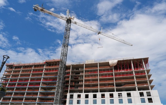 A tower crane raises the final structural beam into the sky at a topping-out ceremony for Hilton Richmond The Mondelle