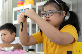 Photograph of young girl with autism working on an art project in a classroom.