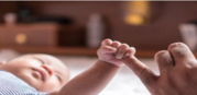 Baby holding adult finger