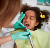 Young girl sitting in a dental chair while a dentist examines and treats her teeth in a dental office.
