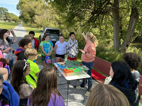 Students listen to outdoor presentation at a folding table in Chilhowie Town Park.