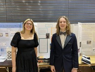Two smiling students in front of science project display boards.