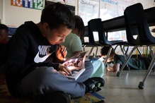A young student reading with a flashlight in a classroom.