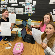 Four students hold up their pen pal letters