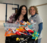 Two smiling teachers pushing a cart full of snacks