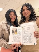 Two smiling students holding up the publication they are featured in