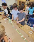 Students building a rollercoaster out of straws and tape