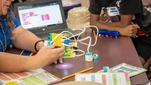 A teacher handling a lego machine with wires