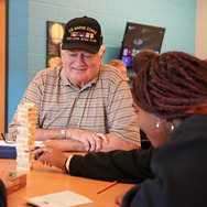 A student playing Jenga with a veteran