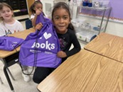 A student holding up a bag saying "I love books"