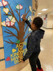 Student adding a message to a Virginia Kindness Week display
