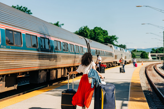 person with suitcase boarding Amtrak train