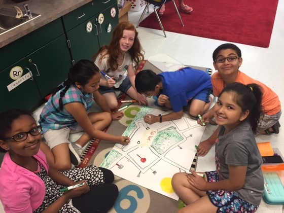 photo of 6 students on floor drawing a poster together