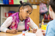 Kindergarten students help each other out during morning work.